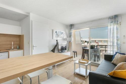 une cuisine et un salon avec une table et un canapé dans l'établissement Appartement T3 terrasse vue sur mer, piscine, parking, wifi et clim, à Sète