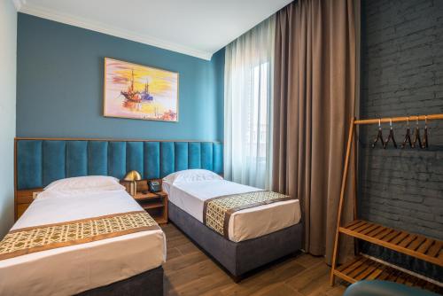 two beds in a hotel room with blue walls at Grand Opera Hotel in Kutaisi