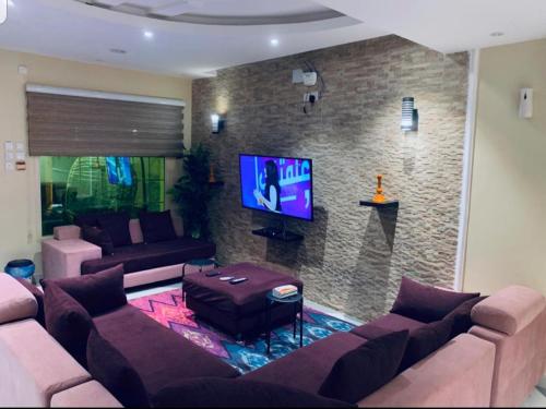 ein Wohnzimmer mit einem Sofa und einem TV in der Unterkunft شاليهات شاطئ ارينا in Qarār