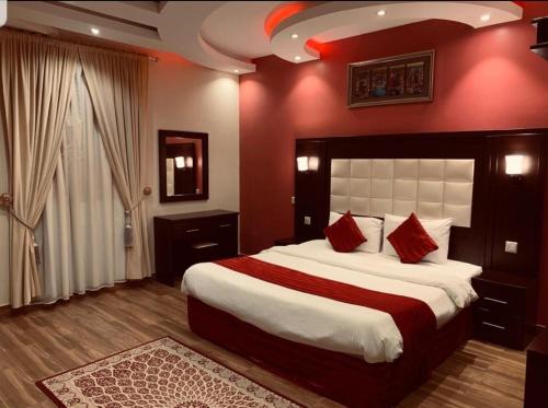 a bedroom with a large bed with red walls at شاليهات شاطئ ارينا in Qarār