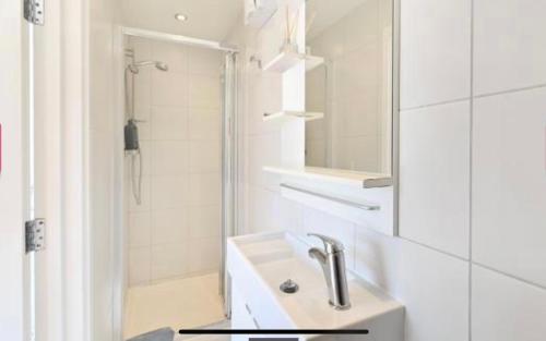 a white bathroom with a sink and a shower at Bright 1 Bedroom Central London in London