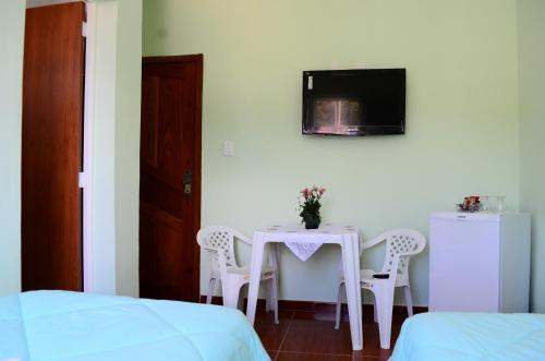 Habitación con mesa con sillas y TV. en Hotel JM Ferreira, en Caeté