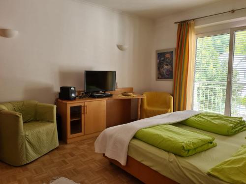 a bedroom with a bed and a chair and a television at Appartement Bürgerbräu Hermagor in Hermagor