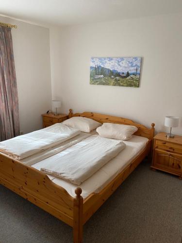 a bedroom with a wooden bed with white sheets and pillows at Ferienwohnung Pitzer in Missen-Wilhams