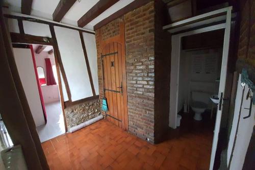 Cette chambre est dotée d'un mur en briques et d'une porte en bois. dans l'établissement Chaumière du Château d'ô et sa mini ferme ,Gite 17 couchages, à Goupillières