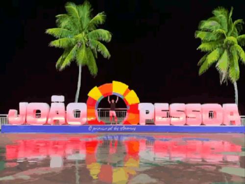 un cartel en un complejo con dos palmeras en Pousada Refúgio en João Pessoa