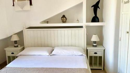 a bedroom with a white bed with two nightstands and two lamps at Villa Maris Capo Vaticano in Capo Vaticano