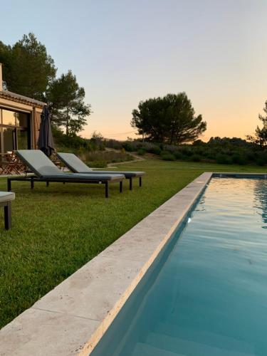 a swimming pool with lounge chairs next to a house at La Bergerie du Roy-Chambres D'hôtes- in Rognes