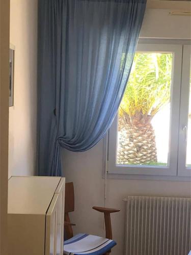une chambre avec un rideau bleu et une fenêtre dans l'établissement La Treize, à Laroque-des-Albères