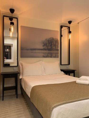 a bedroom with a bed with two tables and two mirrors at Merim Apartments in Ponte de Lima