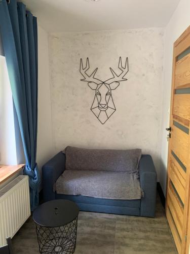 a living room with a couch and a deer head on the wall at Zielona Prowincja in Mysłakowice