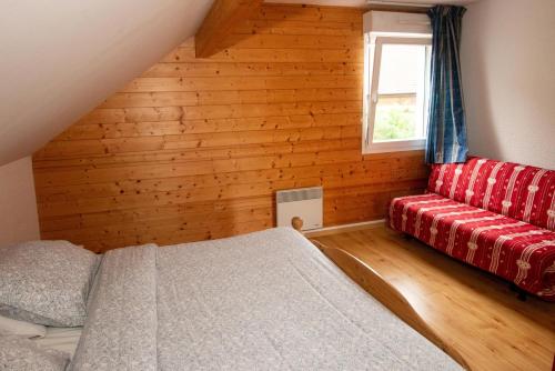 a bedroom with a red couch and a window at Les Adrets in Gérardmer