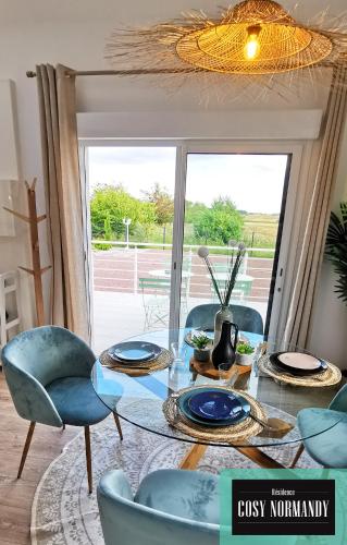 une salle à manger avec une table en verre et des chaises bleues dans l'établissement Cosy Normandy - 04, à Bois-Jérôme-Saint-Ouen