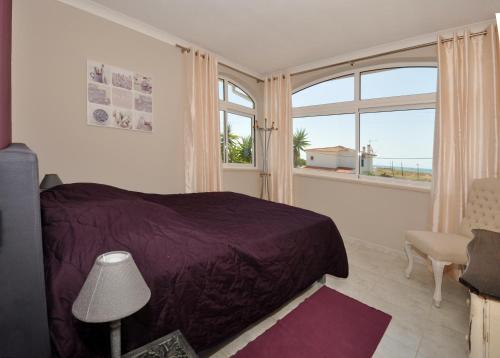a bedroom with a purple bed and a large window at Beachhouselagos in Lagos