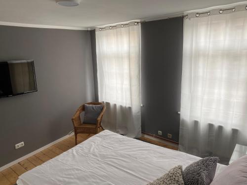 a bedroom with a bed and a chair next to a window at Altstadt Fereienwohnung Hameln in Hameln