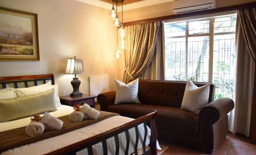 a bedroom with a bed and a couch and a window at LUXURY ROOM @ 4 STAR GUEST HOUSE in Middelburg