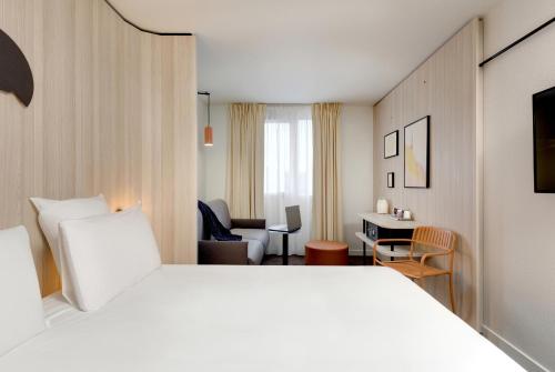 Habitación de hotel con cama blanca y escritorio en Kyriad Clermont-Ferrand-Sud - La Pardieu en Clermont-Ferrand