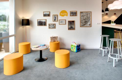 a room with yellow stools and a table at Kyriad Clermont-Ferrand-Sud - La Pardieu in Clermont-Ferrand