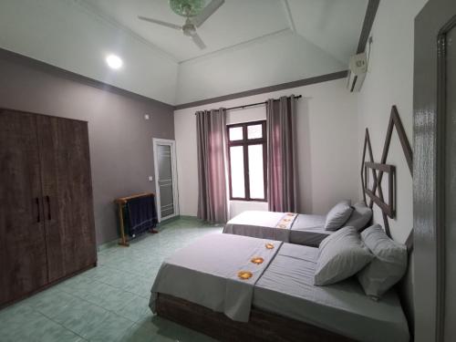een slaapkamer met 2 bedden en een raam bij Boegas View Guesthouse in Vaikaradhoo