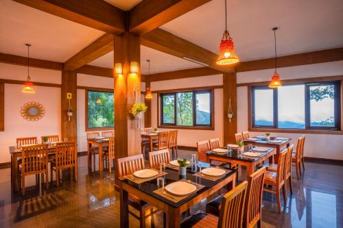 um restaurante com mesas e cadeiras de madeira e janelas em Zostel Munnar em Munnar
