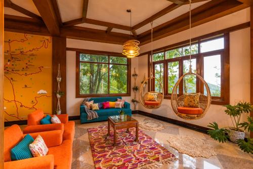 una sala de estar con muebles y ventanas de color naranja. en Zostel Munnar, en Munnar