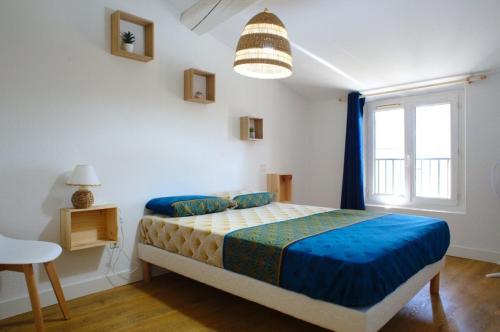 una camera da letto con un letto con lenzuola blu e una finestra di T3 cosy au centre de Castelnaudary a Castelnaudary