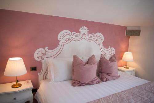 a bedroom with a white bed with pink and white pillows at Maison Tuscany Bed&Breakfast in Sinalunga