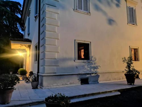 a side view of a white building with potted plants at Maison Tuscany Bed&Breakfast in Sinalunga