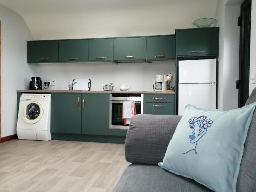 a kitchen with green cabinets and a couch with a pillow at Self catering upstairs apartment at Tradcottage in Sligo