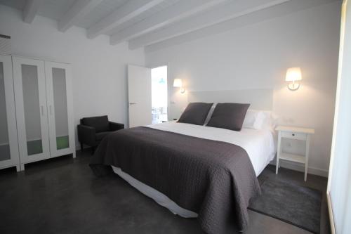 a white bedroom with a bed and a chair at Apartamento 1 dormitorio, jardín y piscina - Apartamentos Montesomo in Somo