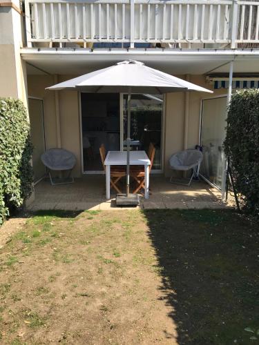 a table and chairs under an umbrella on a patio at Studio L'Air Marin avec terrasse et jardinet à 2 pas de la plage in Pornichet