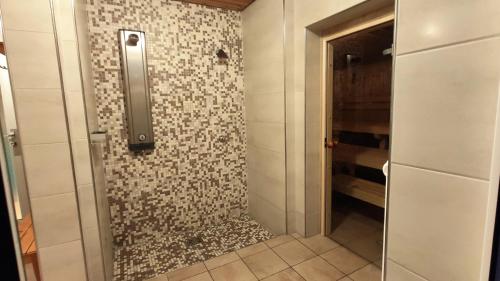 une douche avec une porte vitrée dans une salle de bain dans l'établissement Ferienwohnung AlpenGlück im Ferienpark Oberallgäu mit Hallenbad, Sauna, WLAN, à Missen-Wilhams