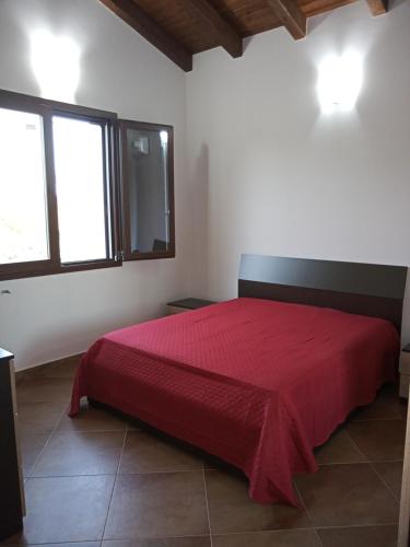 a red bed in a white room with two windows at CASA RURALE IMPASTATO in Montevago