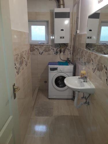 a bathroom with a washing machine and a sink at Napsugár apartmanház in Balatonlelle