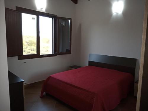a bedroom with a red bed and a window at CASA RURALE IMPASTATO in Montevago