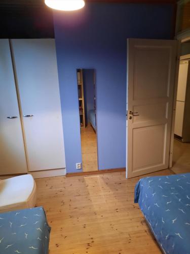 a bedroom with blue walls and a bed and a door at vierashuone in Oulu
