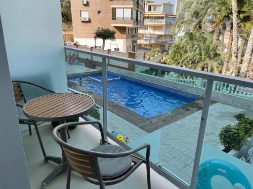 un balcone con tavolo, sedie e piscina di Calle la Cala, 2 a Benidorm