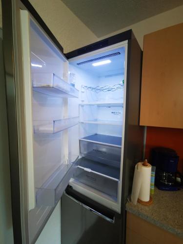 an empty refrigerator with its door open in a kitchen at Ferienwohnung Kaiserblick in Stephanskirchen