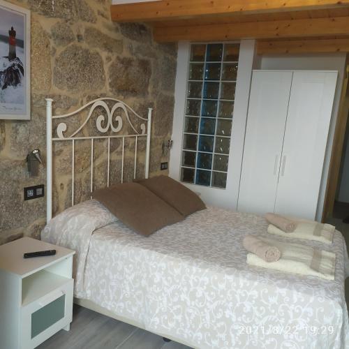 a bedroom with a bed and a stone wall at Vilar Norte in Bueu