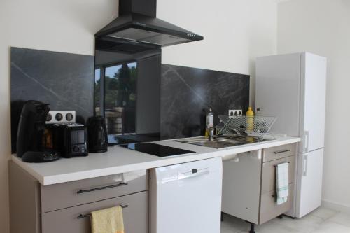 une cuisine avec un évier et une cuisinière dans l'établissement Maison neuve calme avec jardin et parking 15 mn de la Grande Motte et du Grau du roi ACCES PMR, à Marsillargues