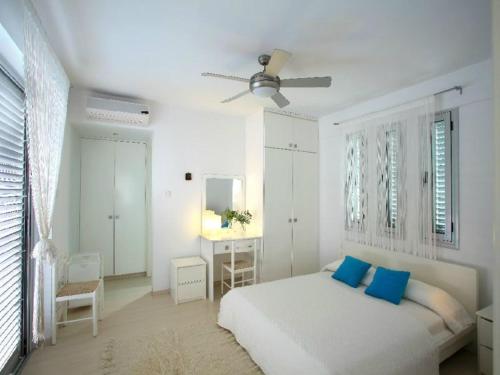 ein weißes Schlafzimmer mit einem Bett mit blauen Kissen in der Unterkunft Architect's Villa in Protaras
