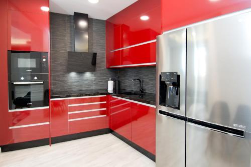 a red kitchen with stainless steel appliances and red cabinets at Condo San Bernardino by Kivoya in Madrid