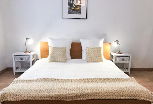 een slaapkamer met een wit bed en 2 nachtkastjes bij La Maison bleue in Arles