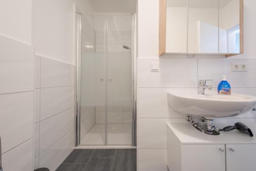 une salle de bain blanche avec lavabo et douche dans l'établissement Merve Comfort Aparts4-Hannover, à Hanovre