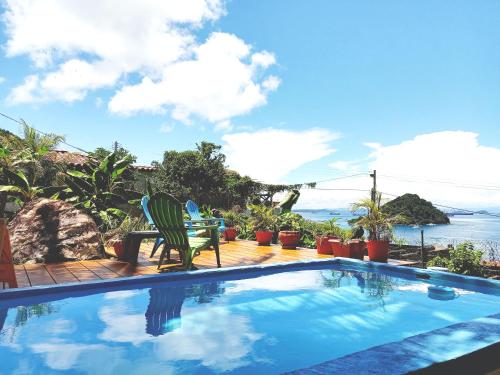 una piscina con 2 sillas y el océano en Cerrito Tropical Eco Lodge, en Taboga