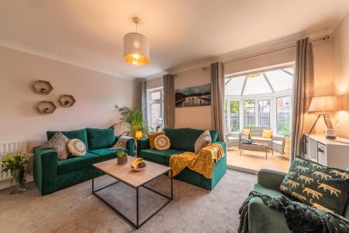 a living room with green couches and a table at 3 Bed Spacious Stylish House, Southampton - Off Road Parking & Private Garden - Sleeps 7, Close to City Centre - by Blue Puffin Stays in Southampton