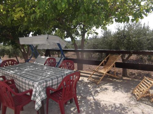 einen Tisch mit roten Stühlen und einem weißen Regenschirm in der Unterkunft La Casina Bianca in Seccagrande