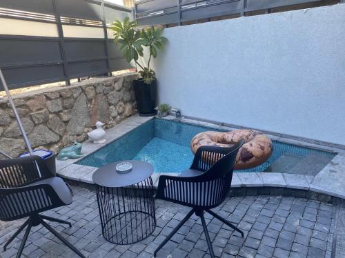 ein Swimmingpool mit zwei Stühlen und einem Tisch in der Unterkunft daniela in Eilat