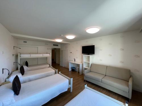 a room with two beds and a couch and a television at Albergue Guiana in Ponferrada