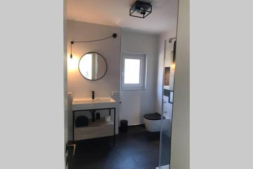 uma casa de banho com um lavatório, um espelho e um WC. em Cosyinlaboe em Laboe